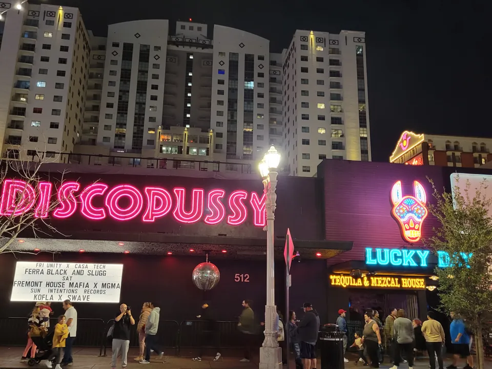 Letrero de Discopussy y acceso 512 junto al vecino Lucky Day de noche.