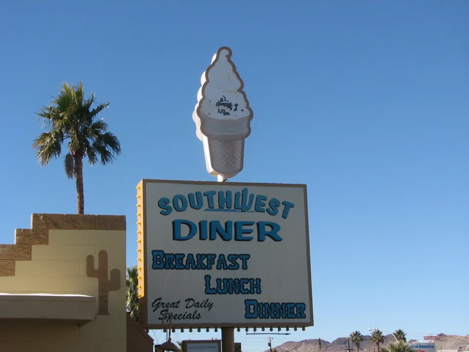 Letrero de Southwest Diner coronado por una figura de helado, con una palmera al lado.