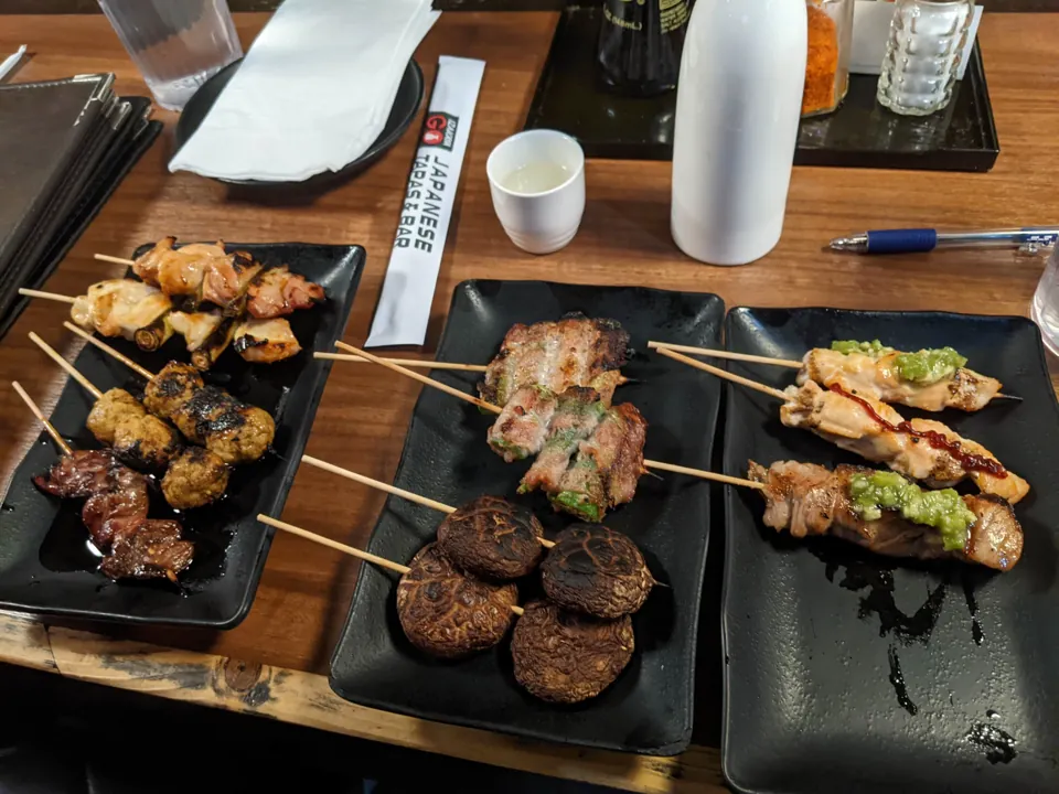Varios platos de brochetas en una mesa de Izakaya Go.