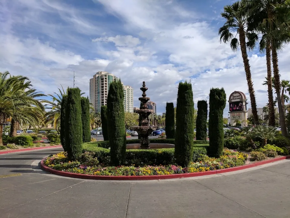 Acceso ajardinado, fuente y letrero de Tuscany Suites & Casino
