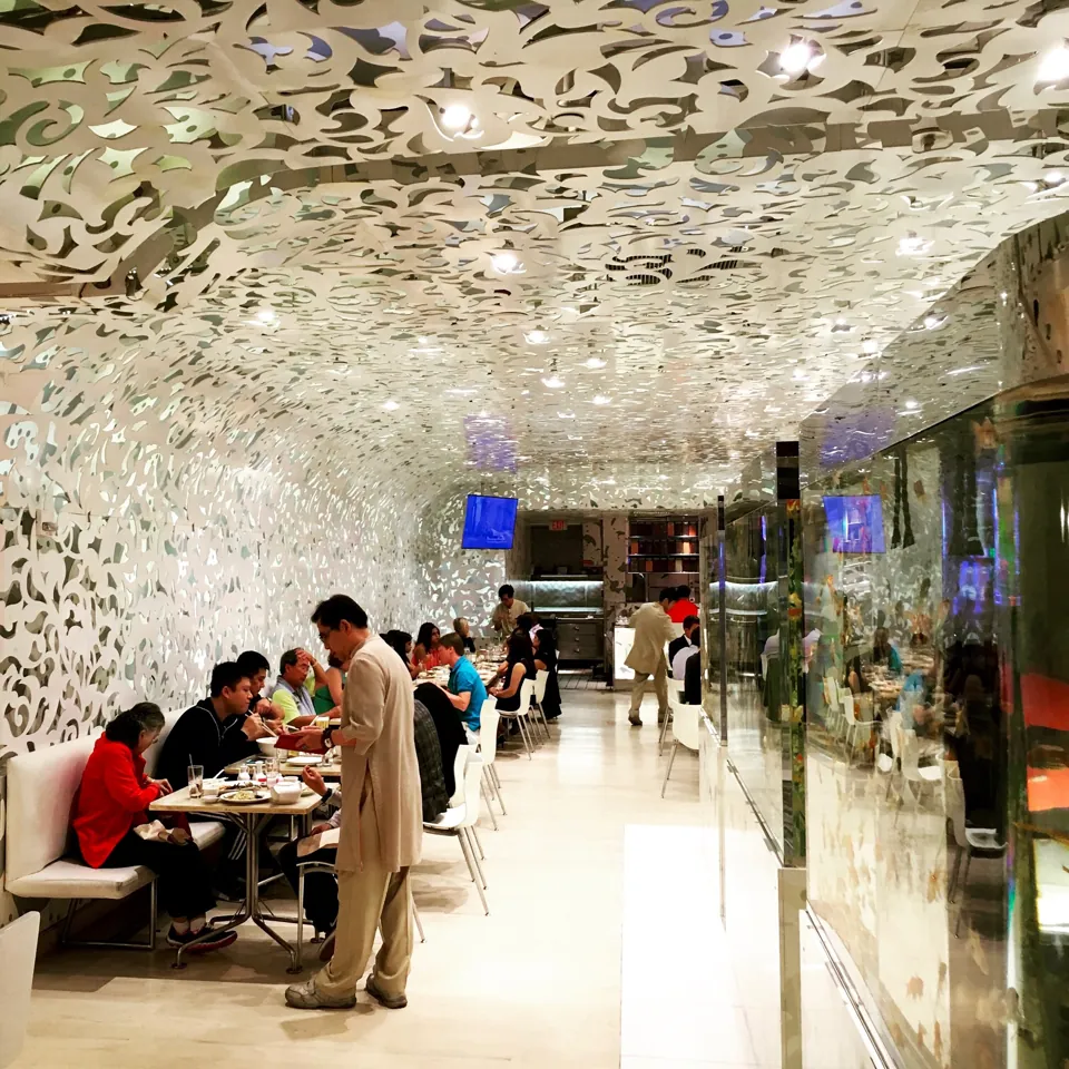 Comedor de Beijing Noodle No. 9 con mesas y techo blanco decorado.