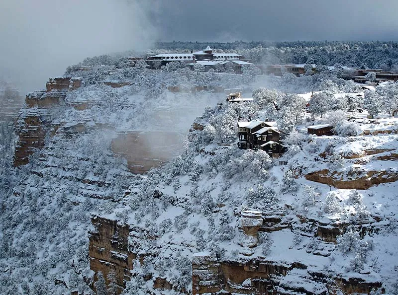 Edificios de Grand Canyon Village junto al cañón y árboles cubiertos de nieve.