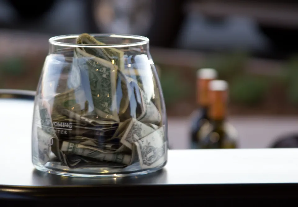 Recipiente con billetes para propinas en un bar · fotografía ilustrativa de 2010