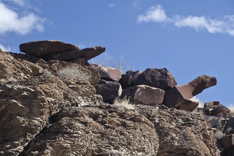Rocas oscuras con grabados en Sloan Canyon bajo un cielo azul.